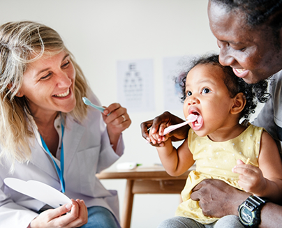 Childrens dentist showing a toddler and mom how to brush teeth