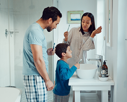 Mother father and young son brushing their teeth together