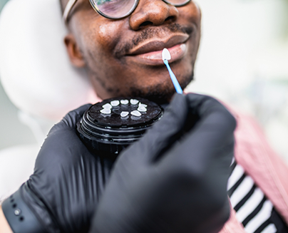 Dentist holding a veneer in front of a patients smile