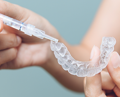 Person placing gel into a teeth whitening tray