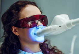 Woman in dental chair receiving professional teeth whitening