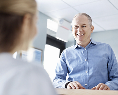 Man smiling at dental office receptionist