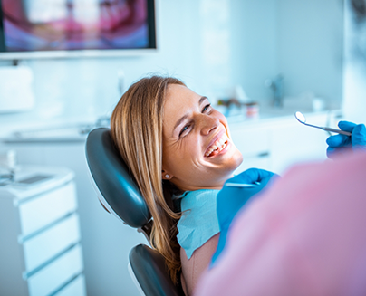 Woman in dental chair grinning at her dentist