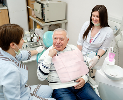 Senior man talking to his dentist while pointing to his mouth