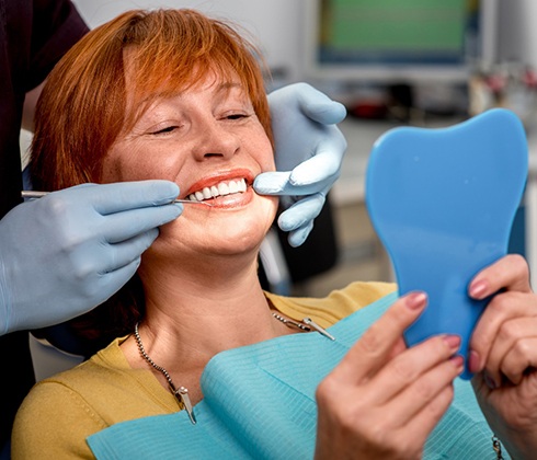 older woman smiling in dental mirror 