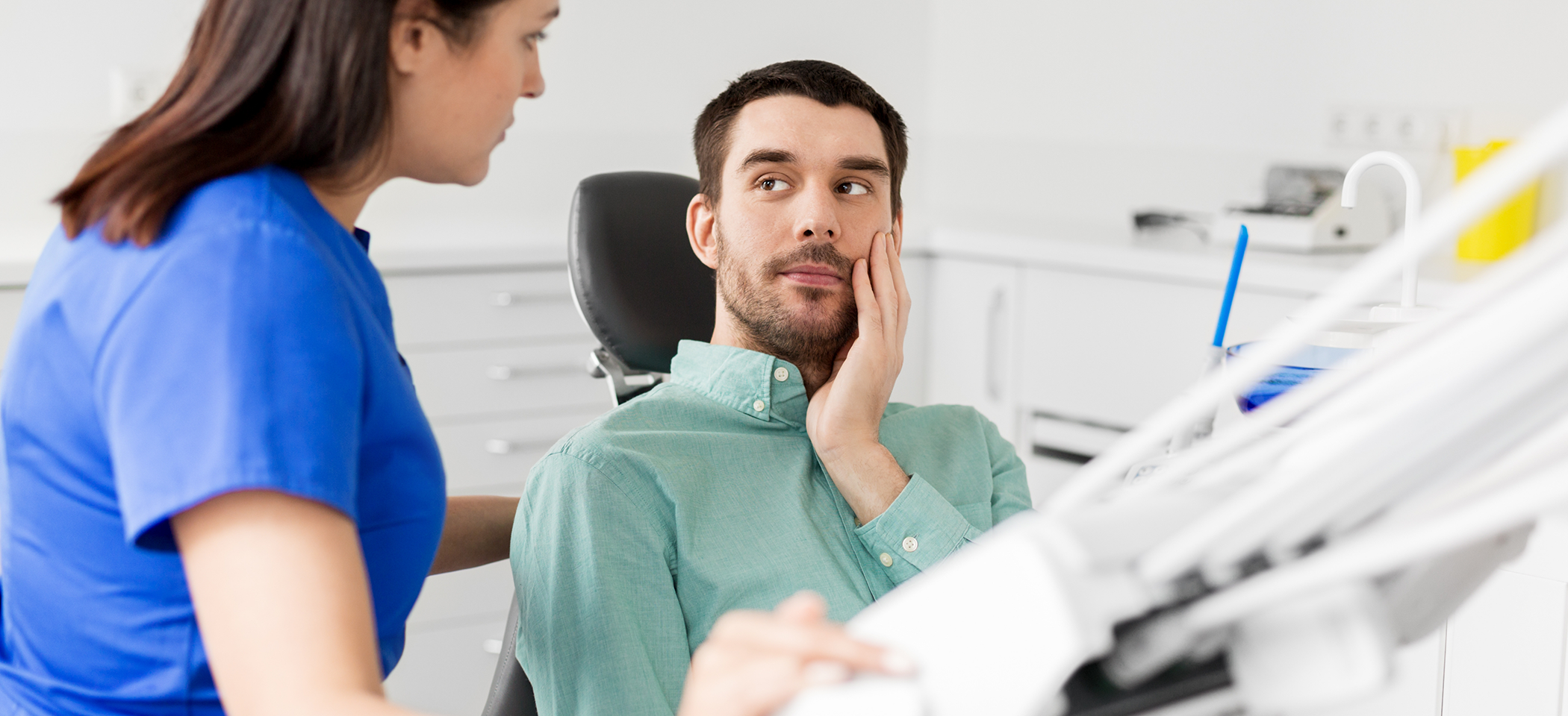 Man holding his cheek in pain while talking to his emergency dentist in Cleburne