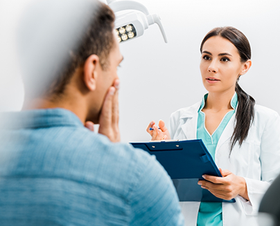 Dentist listening to a patient who is holding their cheek in pain