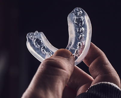 Hand holding a clear athletic mouthguard