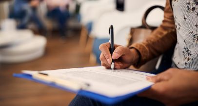 Person filling out paperwork on a clipboard