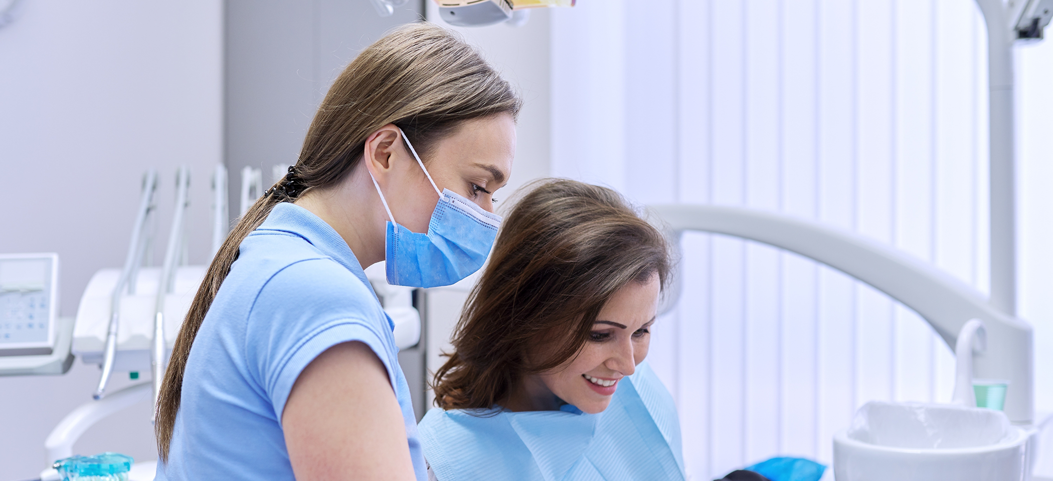 Dental team member talking to a woman in the dental chair