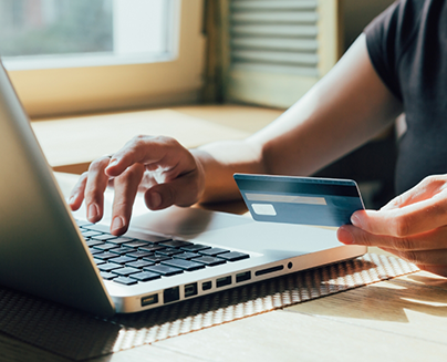 Person typing their payment card information into a laptop