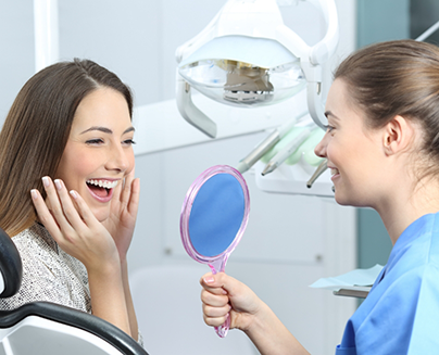 Dental hygienist holding a mirror to show a patient her smile