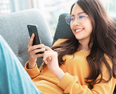 Young woman smiling while scrolling on her phone