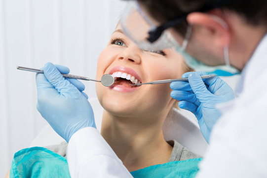 dentist looking in patient’s mouth 